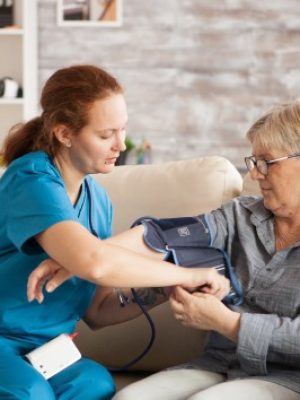 female-nurse-using-digital-blood-pressure-device-senior-woman-nursing-home